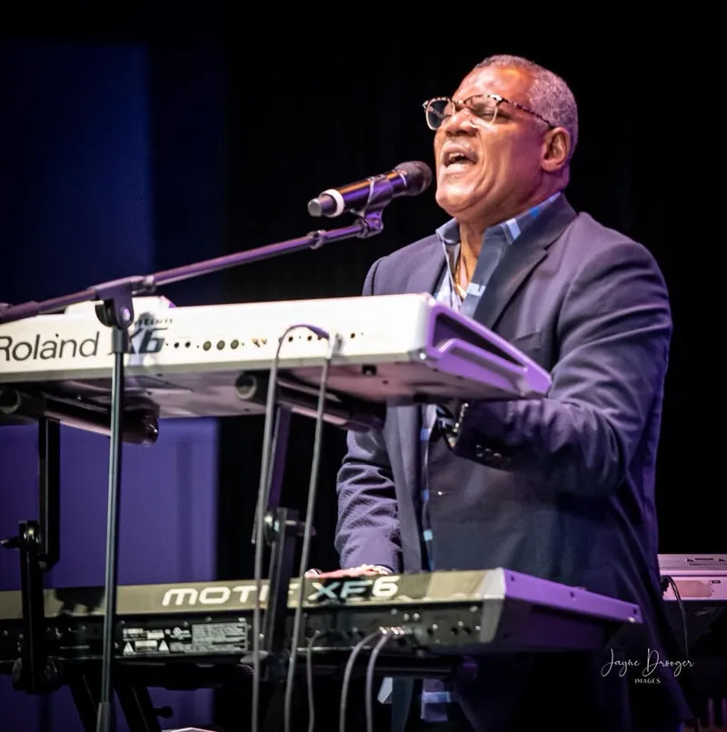 Shawn Brown sings into a microphone while playing stacked Roland and Motif XF6 keyboards on stage