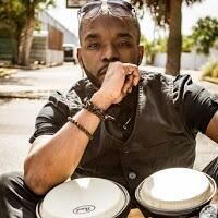 Mark Harris seated behind a pair of drums outdoors